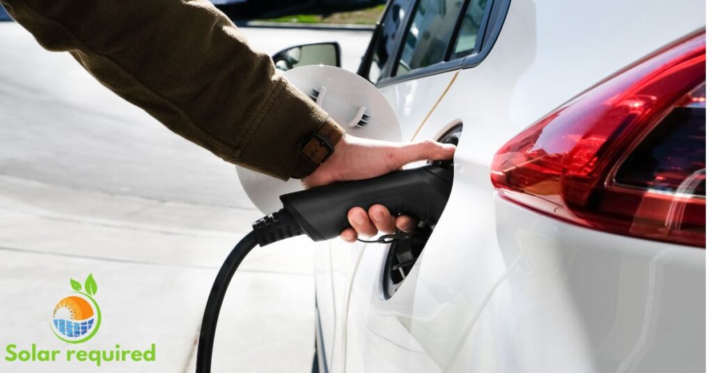 A person charging an electric car with a plug-in charger.