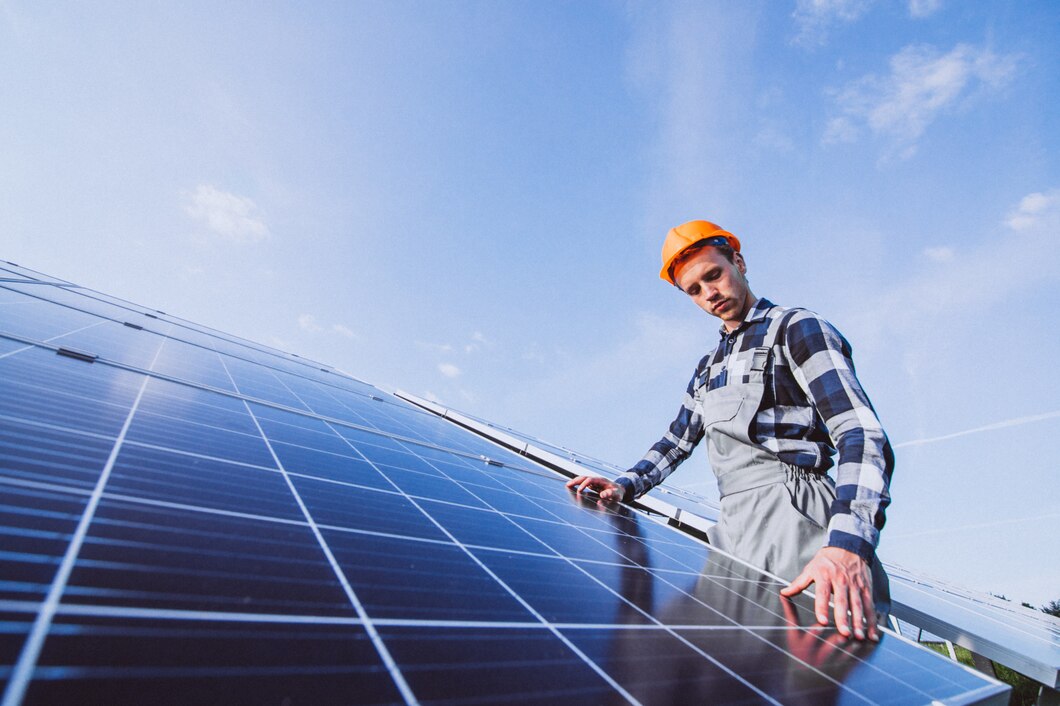 a man in a hard hat standing next to a solar panel